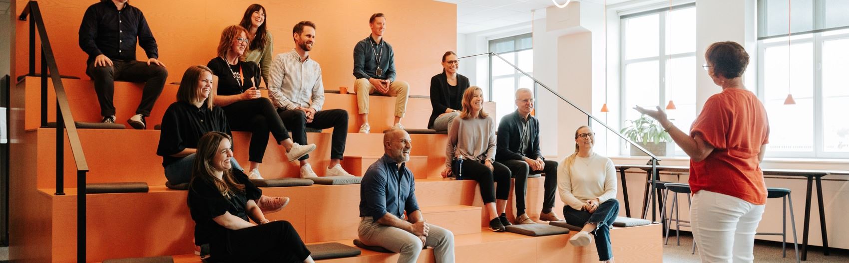 Medarbetarna sitter och lyssnar i en gradäng.