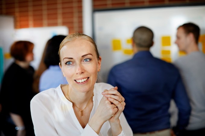 Kvinna i förgrunden med arbetsgrupp i bakgrunden